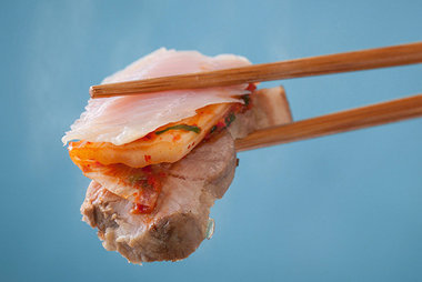 먹음직스러운 홍어,돼지고기,김치를 포개어 든 한젓가락