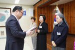 4월 정례조회에서 정장을 입은 남성이 종교복과 안경을 착용한 여성에게 표창장을 전달하는 모습