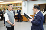 수시인사 임용장 수여식에서 정장을 입은 남성이 회색 니트 조끼를 입은 남성 직원에게 임용장을 전달하는 모습
